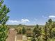 Expansive view showcasing lush trees, rooftops, and a distant mountain, all under a bright blue sky with scattered clouds at 1674 Bent Grass Cir, Castle Rock, CO 80109