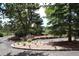 Circular driveway with flowerbeds and trees leading to a home, providing a welcoming and beautifully landscaped entrance at 21849 Cabrini Blvd, Golden, CO 80401
