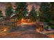 Charming home entrance with stone accents, illuminated driveway, and mature trees at dusk at 21849 Cabrini Blvd, Golden, CO 80401