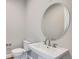 Half bathroom featuring a pedestal sink, a round mirror, and modern fixtures at 574 Agoseris Way, Castle Rock, CO 80104