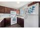 Bright kitchen featuring white appliances, dark cabinets and a window with a view at 20451 Kelly Pl, Denver, CO 80249