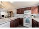 The kitchen features white appliances, dark cabinets, a dining area and an open layout at 20451 Kelly Pl, Denver, CO 80249