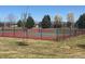Community tennis court with red and green surface, surrounded by a black fence at 20451 Kelly Pl, Denver, CO 80249