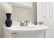 Close-up of a bright white bathroom sink with white decor and chrome hardware and a black vase at 5436 E Atlantic Pl, Denver, CO 80222