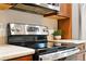 Close-up of stainless steel stove cooktop with granite countertops and wood cabinets at 5436 E Atlantic Pl, Denver, CO 80222