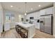 Modern kitchen with white cabinets, stainless steel appliances, and a spacious island with seating at 6745 S Tempe Ct, Aurora, CO 80016