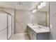 Bright bathroom featuring a double sink vanity with a quartz countertop and a glass-enclosed shower at 13486 Valentia St, Thornton, CO 80602