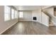 Sunlit living room with hardwood floors, a cozy fireplace, and staircase at 13486 Valentia St, Thornton, CO 80602