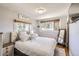 Cozy bedroom with a decorative mirror, a bed dressed in white striped bedding, and two windows at 3280 Fenton St, Wheat Ridge, CO 80212
