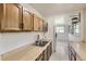Galley kitchen with wood cabinets, stainless steel sink, and white subway tile backsplash at 3280 Fenton St, Wheat Ridge, CO 80212