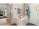 Bathroom featuring a soaking tub with brushed gold fixtures and neutral tile at 2552 E Alameda Ave # 92, Denver, CO 80209