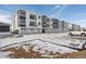 Two-story townhome building with attached garages and snowy landscape at 6153 N Ceylon St # 201, Denver, CO 80249