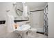 Updated bathroom features tile floor, pedestal sink, built-in shelving, and shower with black and white curtain at 4731 S Acoma St, Englewood, CO 80110
