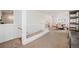 Hallway with tan carpet shows access to dining area with wooden dining table and staircase with white banister at 4731 S Acoma St, Englewood, CO 80110
