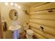 Bathroom features wood-paneled walls, a sink and toilet with rustic decorations, and a custom fishing rod rack at 13525 Woodmoor West Dr, Larkspur, CO 80118