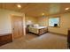 Bedroom with wood paneled wall, light brown carpet, and a queen sized bed at 13525 Woodmoor West Dr, Larkspur, CO 80118