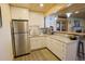Kitchenette with white cabinetry, granite countertops, and stainless steel refrigerator at 13525 Woodmoor West Dr, Larkspur, CO 80118