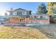 Rear exterior featuring a brick facade, a deck, a well-kept lawn and mature trees at 7649 E Amherst Ave, Denver, CO 80231