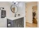 Modern bathroom features a gray vanity, round mirror, and updated fixtures at 3376 Jasmine St, Denver, CO 80207