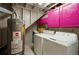 Laundry room with a water heater, washer, dryer, and hot pink cabinets for cleaning needs at 6655 S Elm Cir, Centennial, CO 80121