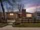 Charming home with a brick chimney and fenced front yard at sunset at 1594 S Locust St, Denver, CO 80224