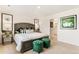 Spacious bedroom with a large bed, green ottomans, and stylish wall art at 22293 E 6Th Pl, Aurora, CO 80018