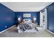Comfortable bedroom featuring gray carpet, blue accent wall and a bed with gray headboard and matching blanket at 1309 Alexandria St, Lafayette, CO 80026