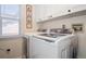 Laundry room features new, front-loading washer and dryer, white cabinets, and natural light from the window at 16084 Stonebriar Dr, Parker, CO 80134