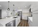 Bright, white kitchen features an island, stainless steel appliances, and modern pendant lighting at 5292 Columbine Ln, Denver, CO 80221