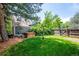 Lush backyard with a hot tub, privacy fence, mature trees, and well-maintained lawn at 6360 S Kendall St, Littleton, CO 80123