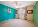 Empty bedroom with teal accent wall, ceiling fan, window, and green closet doors at 6360 S Kendall St, Littleton, CO 80123