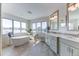 Bathroom featuring a soaking tub under large windows, double sink vanity with grey cabinetry and tiled floors at 2035 Buchanan Pt, Lafayette, CO 80026