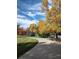 A serene view of a curved walking path flanked by trees in fall colors and a beautiful blue sky at 8617 Gold Peak Dr # D, Highlands Ranch, CO 80130