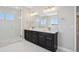 Bathroom featuring a double vanity with dark cabinets and a walk-in shower with clear glass doors at 2125 S Orion St, Lakewood, CO 80228