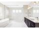 Bright bathroom featuring a soaking tub, frameless shower, double vanity, and tile flooring at 2125 S Orion St, Lakewood, CO 80228