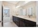 Bathroom featuring double sinks, quartz countertops, dark cabinets, and tile flooring with an adjoining room at 2125 S Orion St, Lakewood, CO 80228