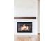 Modern fireplace with a marble surround, wooden mantle, and burning fire at 2125 S Orion St, Lakewood, CO 80228