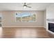 Empty living room featuring hardwood floors, fireplace, ceiling fan and three windows at 2125 S Orion St, Lakewood, CO 80228