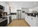 Modern kitchen with stainless steel appliances, white cabinetry, and sleek black backsplash at 6894 Nelson St, Arvada, CO 80004