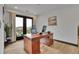 Bright office space with hardwood floors, balcony access, and a large wooden desk at 21345 E 59Th Dr, Aurora, CO 80019