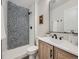 Bathroom featuring a shower with patterned tile, a wooden vanity, and a white sink and toilet at 4591 S Fairplay St, Aurora, CO 80015