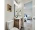 Bathroom with a wooden vanity, toilet, decorative mirror, light gray walls, and tile flooring at 4591 S Fairplay St, Aurora, CO 80015