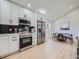 An eat-in kitchen featuring stainless appliances, sleek white cabinets, black tile backsplash, and light wood floors at 4591 S Fairplay St, Aurora, CO 80015