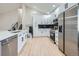 Bright kitchen with stainless steel appliances, black backsplash, white cabinets, and light wood floors at 4591 S Fairplay St, Aurora, CO 80015