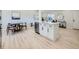 Open kitchen with an island, stainless steel appliances, white cabinets, light wood floors, and dining area at 4591 S Fairplay St, Aurora, CO 80015