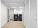 Bright laundry room with front loading washer and dryer, light wood floors and closet with white louvered doors at 6142 Dudley Ct, Arvada, CO 80004