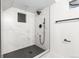Sleek, modern shower featuring black fixtures and dark slate floor, with white marbled tiles at 6142 Dudley Ct, Arvada, CO 80004