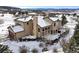 A back view of a large single-Gathering home showcasing its architectural details and snow-covered roof, deck, and yard at 3891 Windchant, Castle Rock, CO 80104