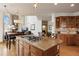 Open kitchen with wooden cabinets and a center island cooktop, open to a living room with a stone fireplace at 3891 Windchant Cir, Castle Rock, CO 80104