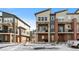 Modern townhomes with brick accents, balconies, and snow-covered landscaping present an attractive exterior view at 7856 W 43Rd Pl, Wheat Ridge, CO 80033